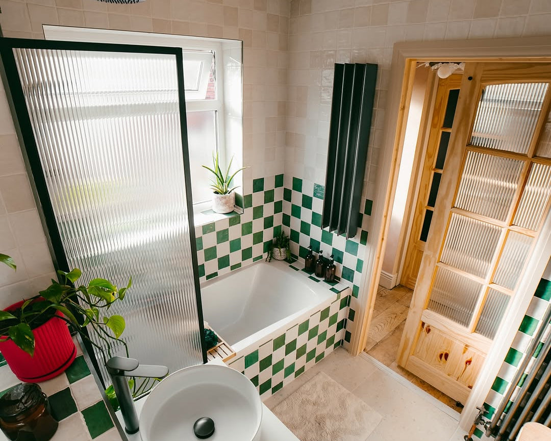 Bathroom with green and white checkered tiles, a bathtub, and a sink.